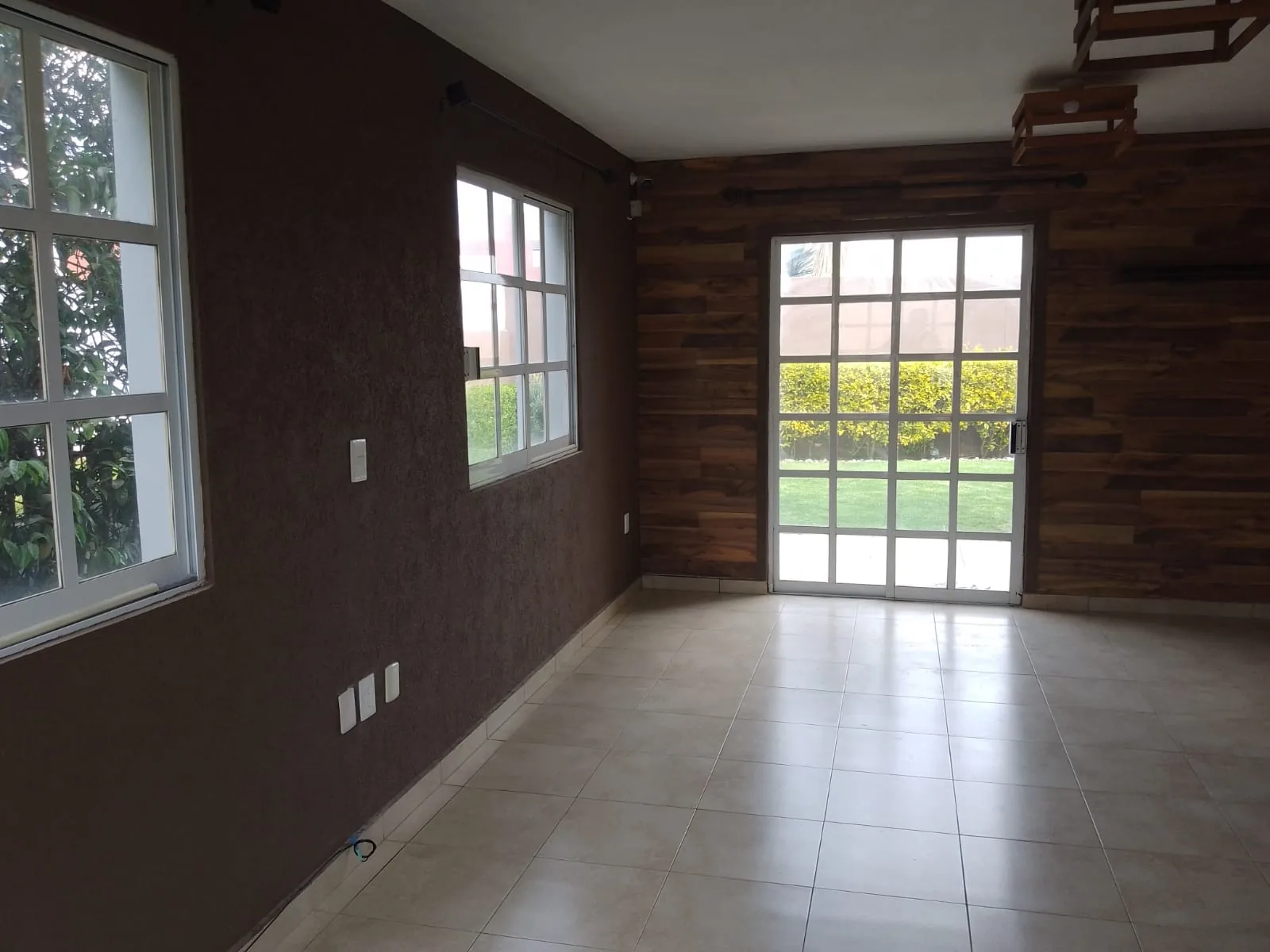 Sala con ventanal de piso a techo hacia el jardín
